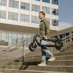 kickscooter-f2-plus-f2-pro-lifestyle-picture-man-carrying-folded-f2-pro-2140×1427-72