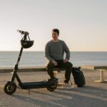 ninebot-kickscooter-max-g2-lifestyle-picture-man-sitting-kickscooter-standing-2140×1427-72